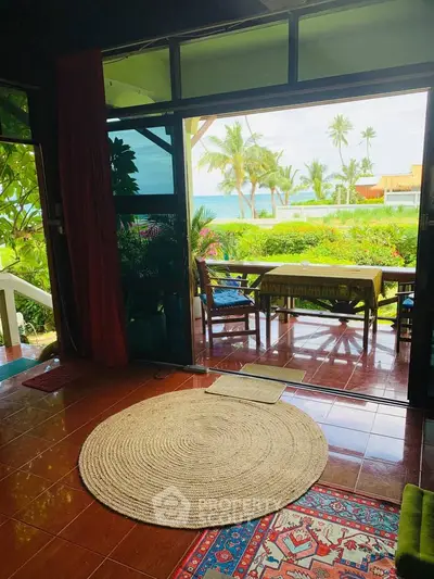 Tropical living room with ocean view and lush greenery, perfect for relaxation.