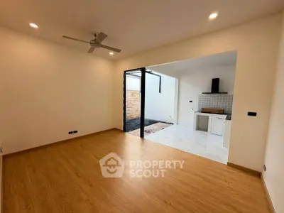 Spacious open-plan living room with wooden flooring and modern kitchen area.