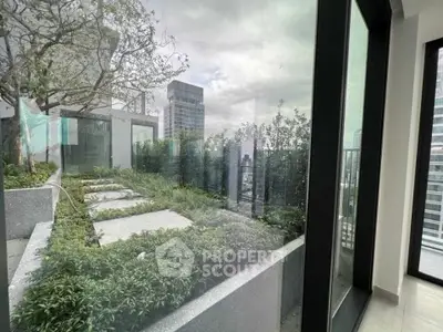 Luxurious urban garden view from modern apartment with large windows and lush greenery.