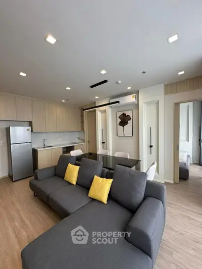 Modern living room with open kitchen, sleek furniture, and bright decor accents.