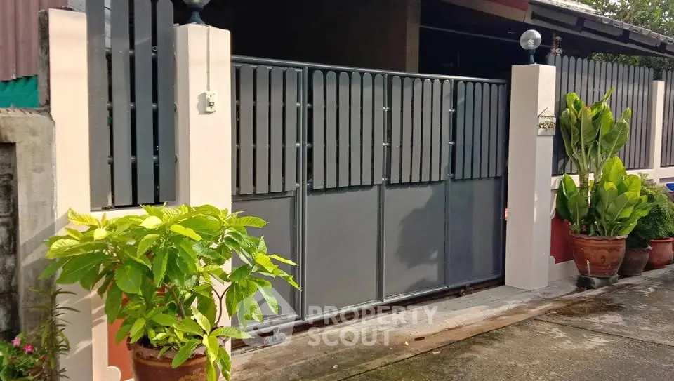 Charming residential entrance with modern gate and lush potted plants