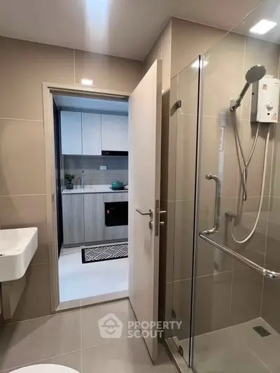 Modern bathroom with glass shower and view into sleek kitchen