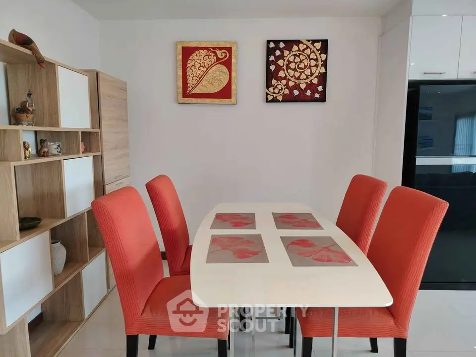 Modern dining area with vibrant orange chairs and elegant wall art, perfect for stylish home gatherings.