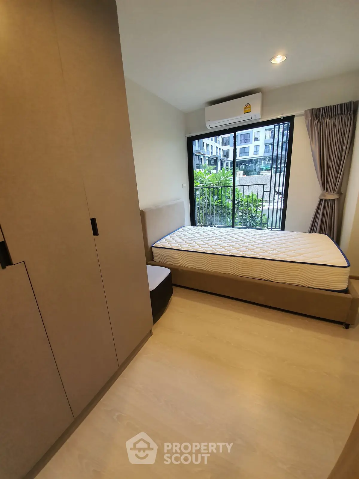 Modern bedroom with large window and built-in wardrobe in urban apartment