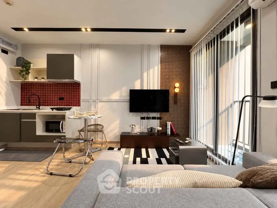 Modern living room with open kitchen, stylish decor, and natural light.