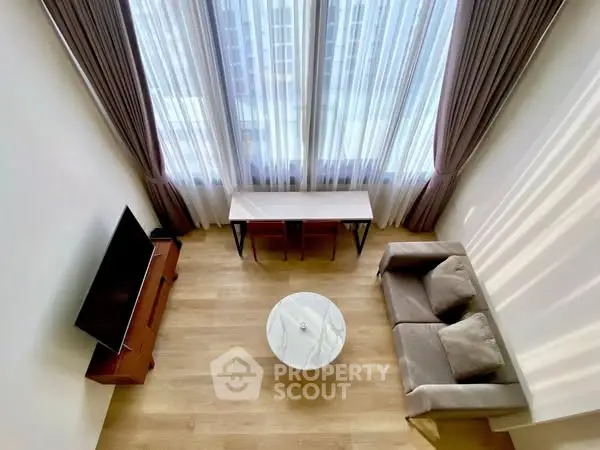 Spacious living room with high ceilings and large windows, modern furniture and wooden flooring.