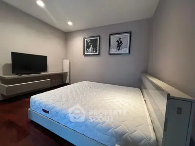 Spacious modern bedroom with stylish decor and mounted TV, perfect for relaxation.