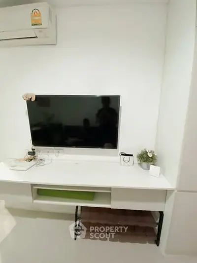 Modern living room with wall-mounted TV and sleek white furniture.