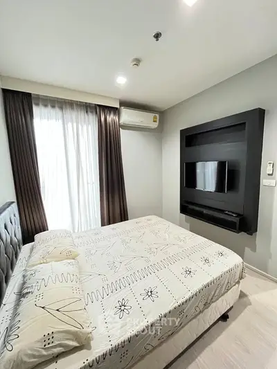 Modern bedroom with stylish decor and wall-mounted TV in a cozy apartment.