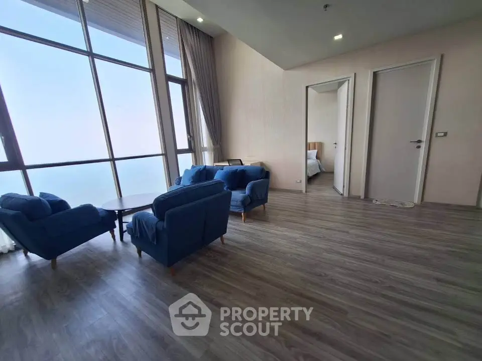 Spacious living room with floor-to-ceiling windows and elegant blue seating, offering a serene ambiance.