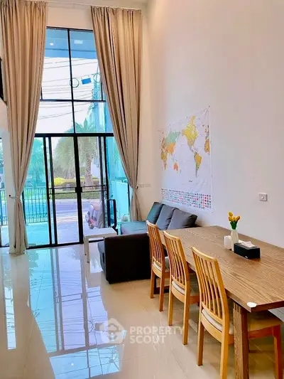 Spacious living room with high ceilings and elegant decor, featuring a large window with garden view.