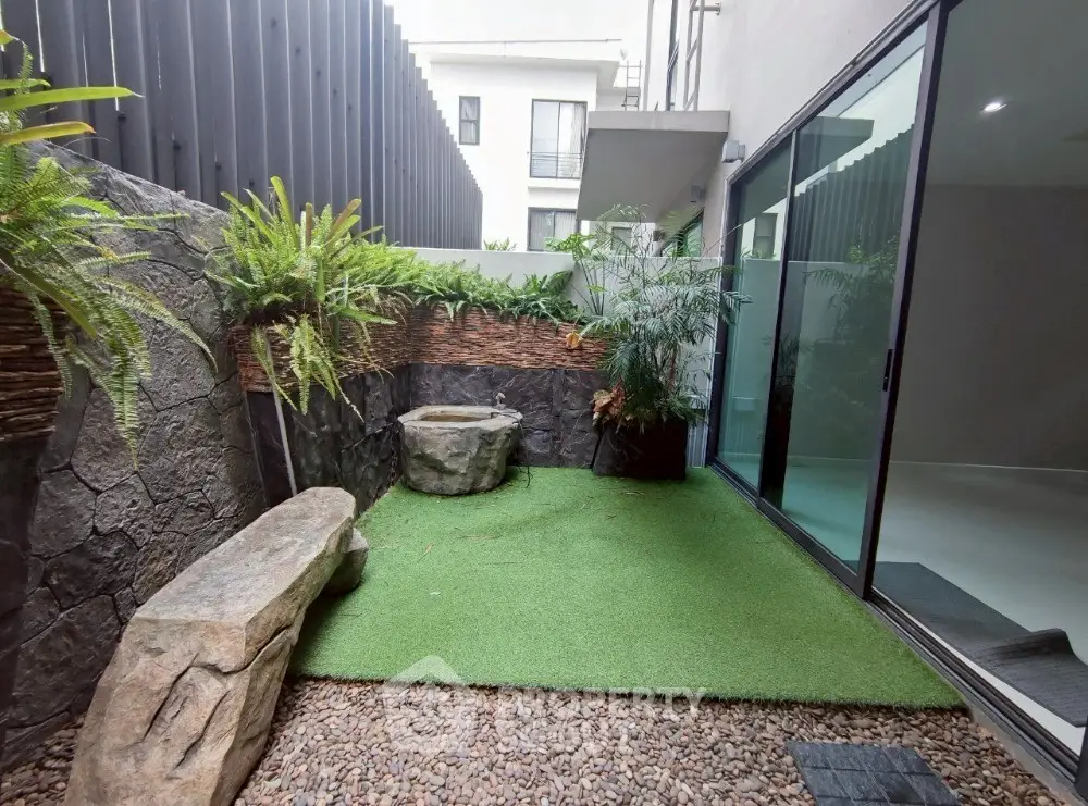 Charming garden patio with artificial grass and stone seating, perfect for relaxation.