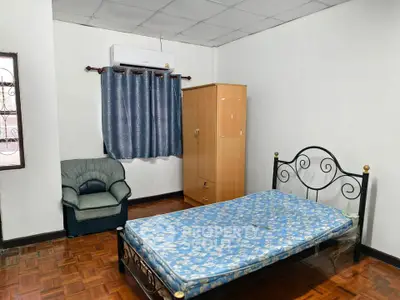 Cozy bedroom with single bed, wardrobe, and armchair, perfect for minimalist living.