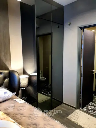 Modern bedroom with sleek mirrored wardrobe and cozy lighting.
