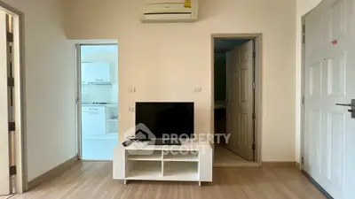 Cozy living room with TV and air conditioning, adjacent to modern kitchen.