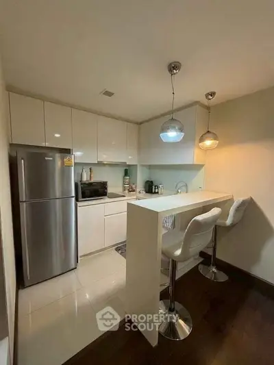 Modern kitchen with sleek white cabinets, breakfast bar, and stainless steel appliances.