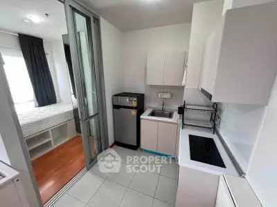 Modern compact kitchen with sleek appliances and adjacent cozy bedroom in a stylish apartment.