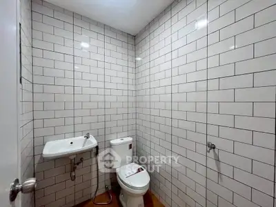 Modern minimalist bathroom with white subway tiles and sleek fixtures.