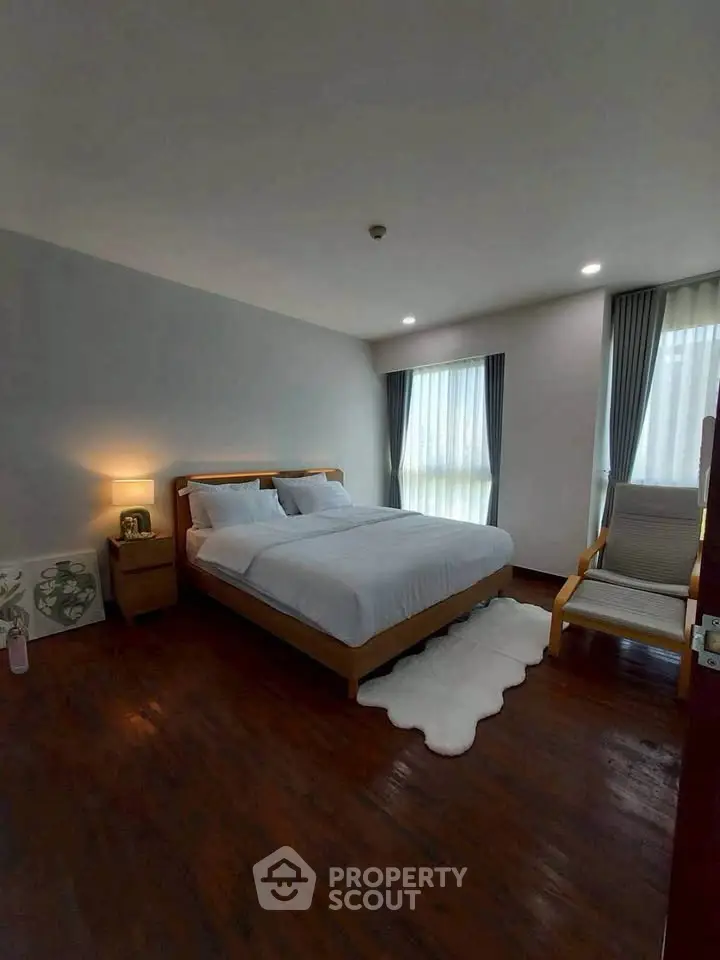 Cozy bedroom with wooden flooring, modern furniture, and soft lighting for a relaxing ambiance.