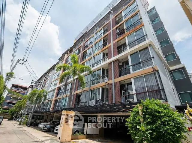 Modern multi-story residential building with balconies and palm trees in urban setting.