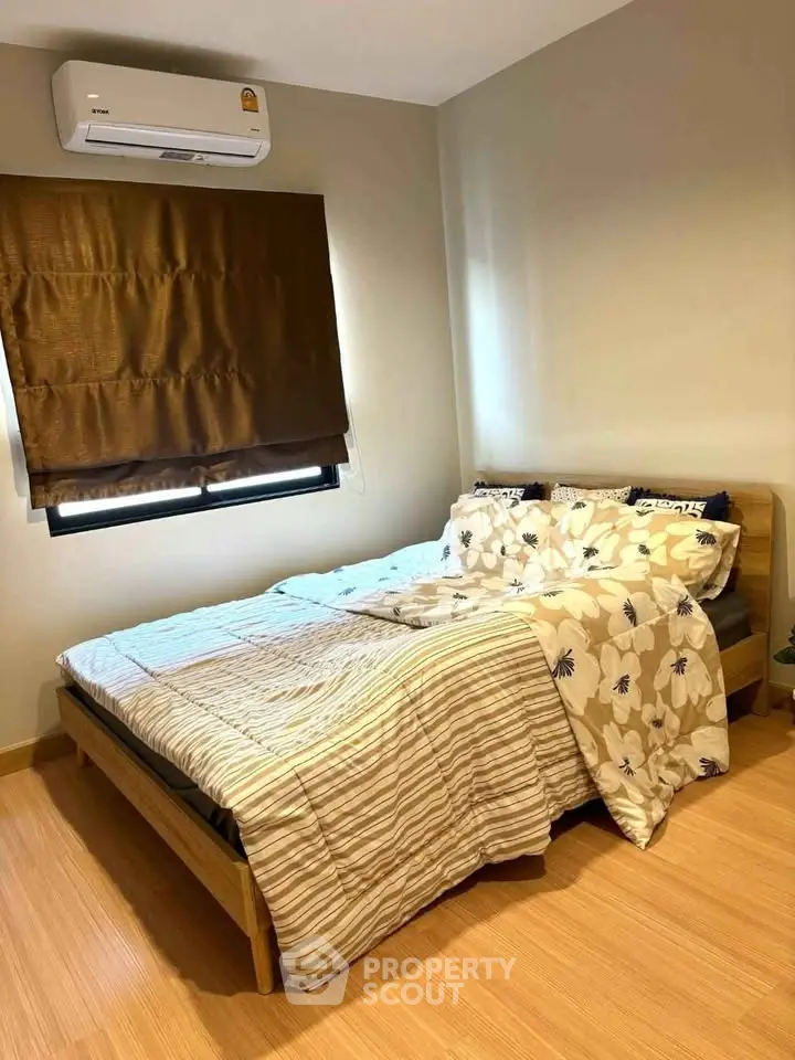 Cozy bedroom with wooden flooring and air conditioning, perfect for relaxation.