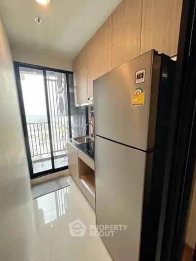 Modern kitchen with sleek appliances and balcony view in a stylish apartment.