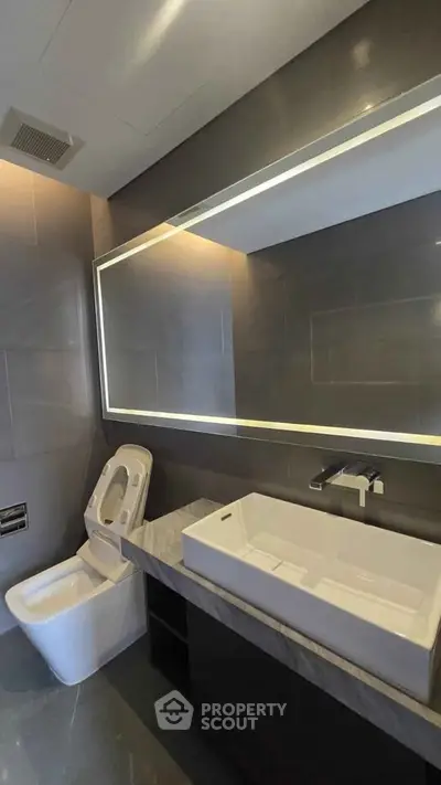 Modern bathroom with sleek fixtures and large illuminated mirror