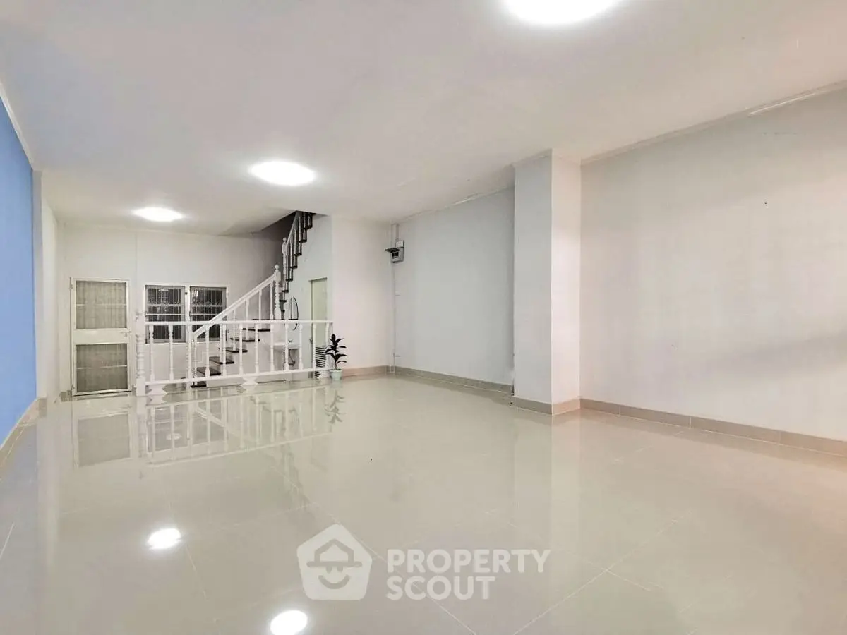 Spacious modern living room with glossy tile flooring and staircase