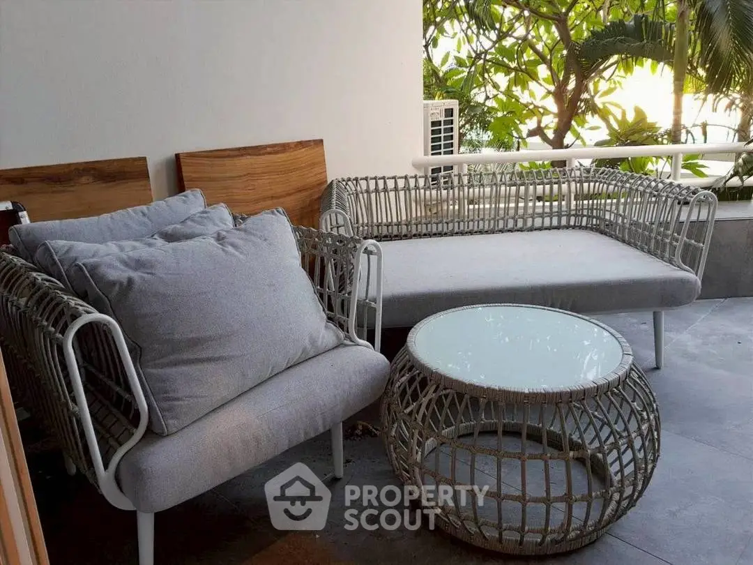 Charming outdoor balcony with cozy seating and lush greenery view.