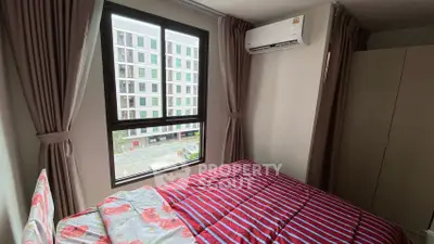 Cozy bedroom with city view, featuring modern air conditioning and vibrant bedding, perfect for urban living.
