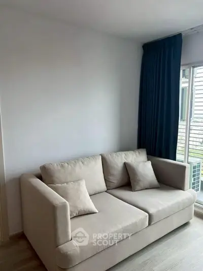 Cozy living room with modern beige sofa and large window with blue curtains