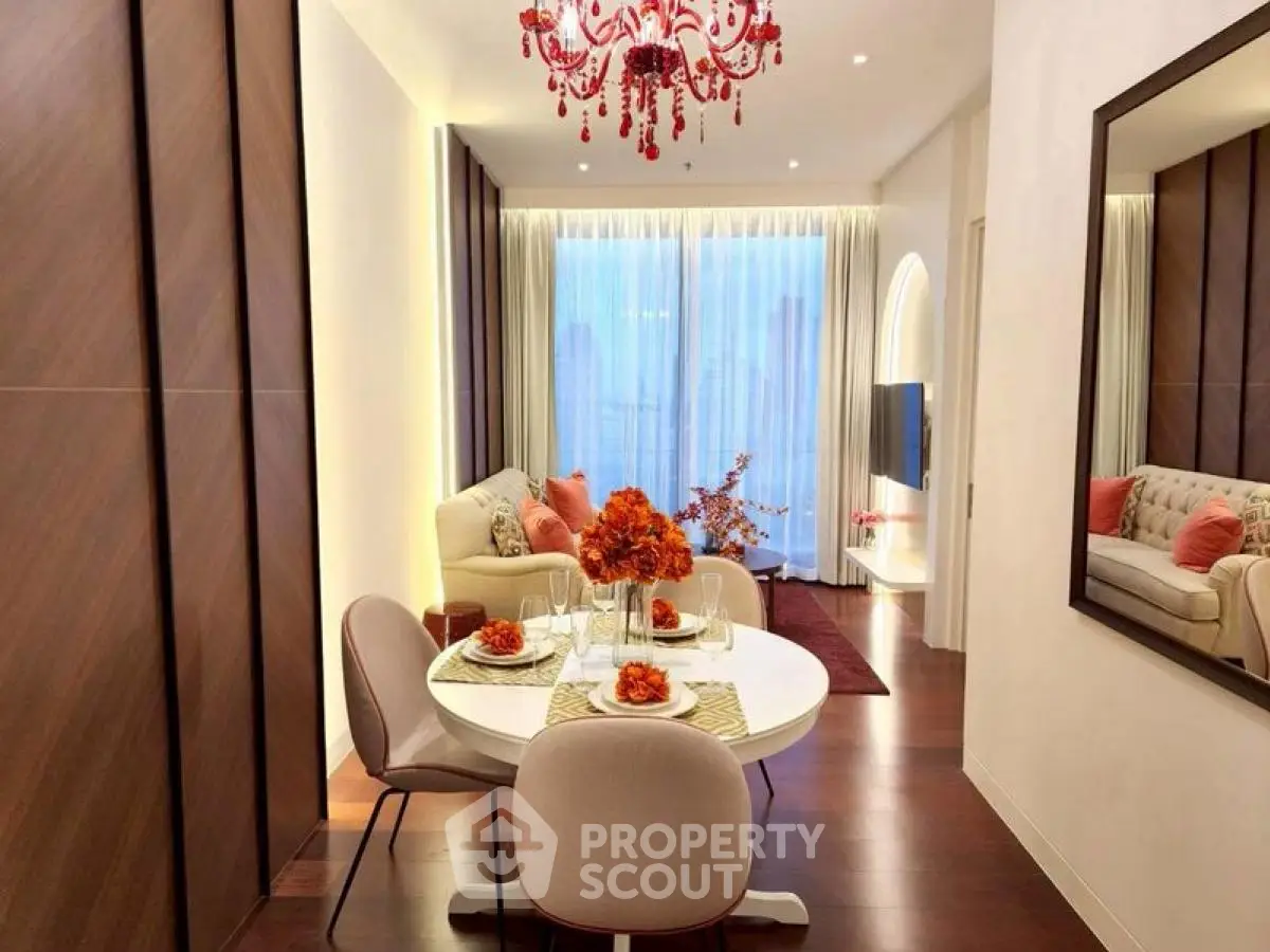 Elegant living room with modern decor and chandelier, featuring a cozy dining area and large window view.