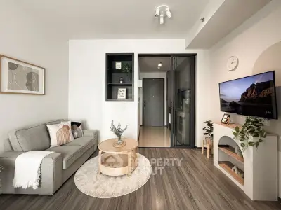 Modern living room with stylish decor and cozy seating area, featuring a wall-mounted TV and elegant wooden flooring.