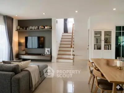 Modern living room with sleek furniture and open layout, featuring a stylish staircase and natural light.