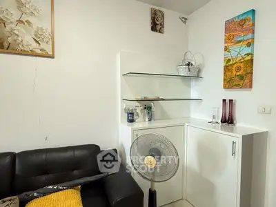 Cozy living room corner with modern decor and fan, perfect for relaxation.