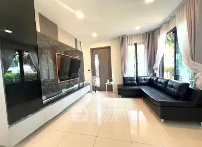 Spacious modern living room with sleek black leather sofa and large TV, perfect for relaxation and entertainment.