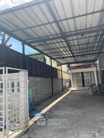 Spacious covered driveway with modern gate and sliding glass doors.