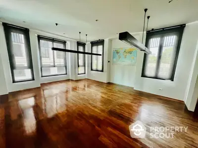 Expansive living room with polished hardwood floors and abundant natural light from multiple windows, perfect for elegant urban living.