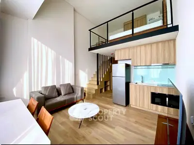 Modern loft apartment with open kitchen and stylish living area, featuring a mezzanine bedroom.