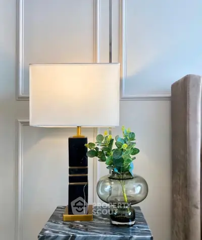 Elegant interior decor with modern lamp and vase on marble table.