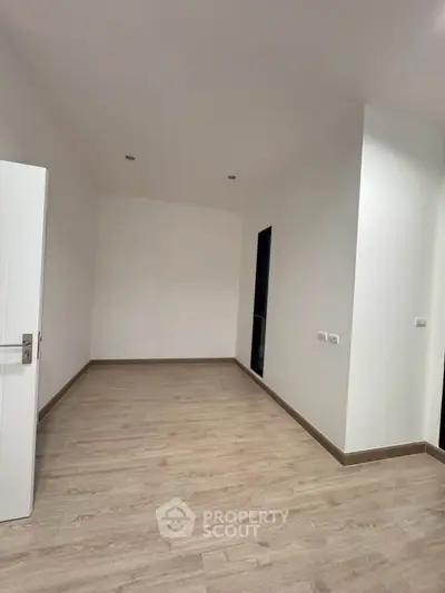 Spacious empty room with wooden flooring and white walls, ready for customization.