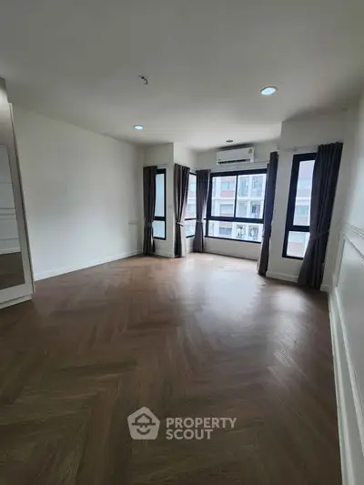 Spacious corner unit living room with large windows and elegant wood flooring.