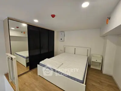 Modern minimalist bedroom with sleek mirrored wardrobe and cozy bed