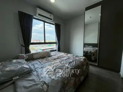 Cozy bedroom with large window offering city views, modern decor, and ample natural light.