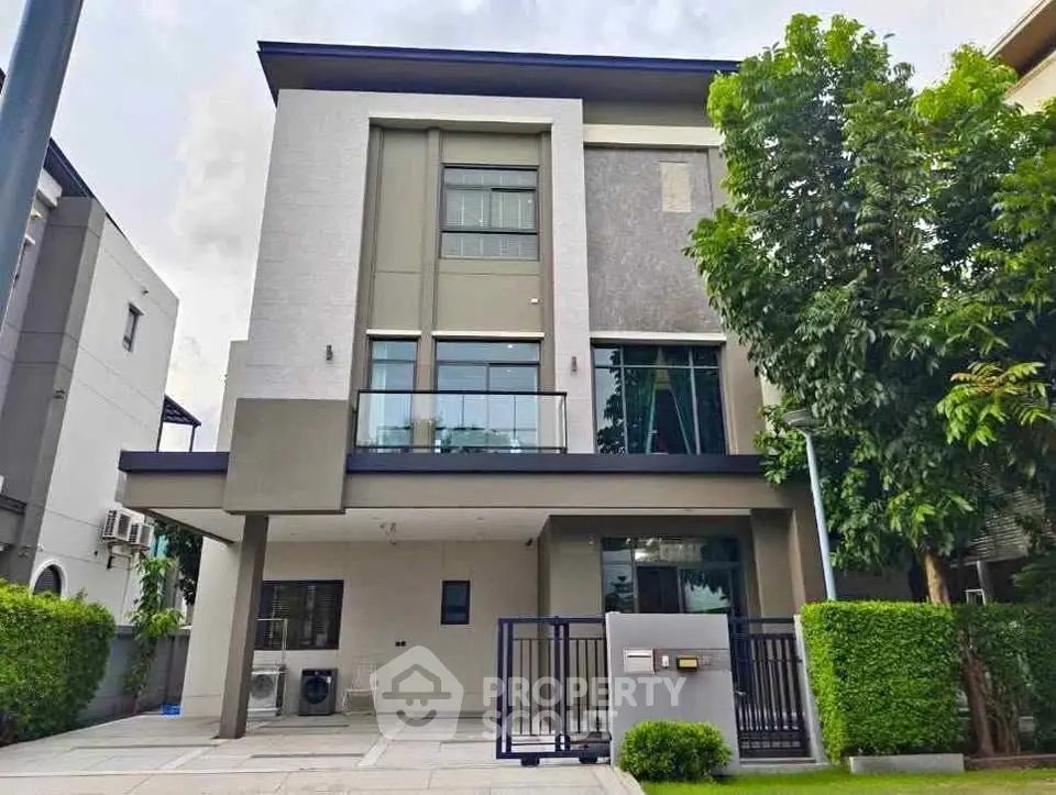 Modern two-story house with large windows and lush greenery in a serene neighborhood.