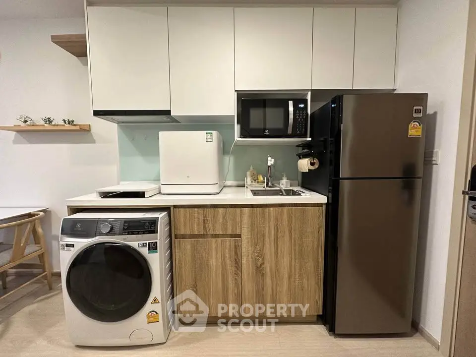 Modern kitchen with sleek appliances and wood cabinetry in compact layout.