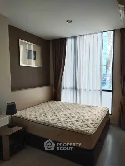 Modern bedroom with large window and minimalist decor in urban apartment.