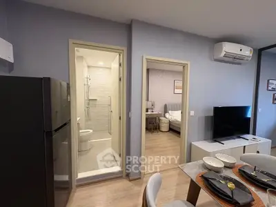Modern apartment interior with open living area, visible bedroom, and sleek bathroom design.