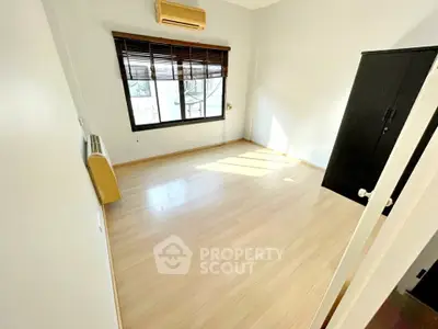 Bright and airy bedroom with wooden flooring and large window in modern apartment.