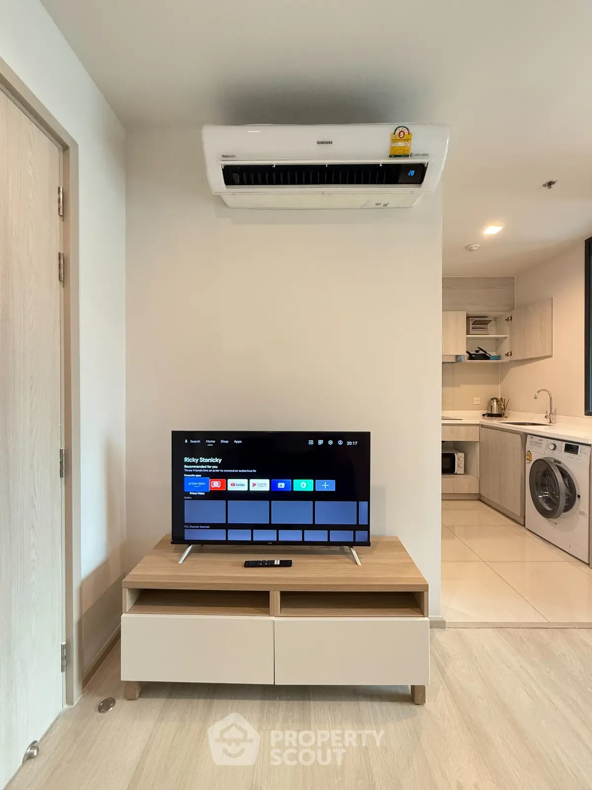 Modern living room with TV, air conditioner, and open kitchen layout